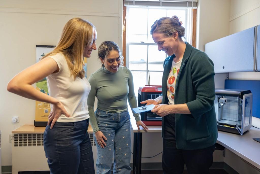 Two students and a professor examine a 3D printed medication container